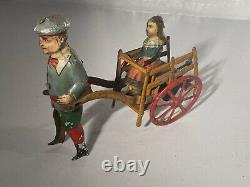 C. 1920 German Issmayer Tin windup Boy pulling Girl in Cart Tin Toy